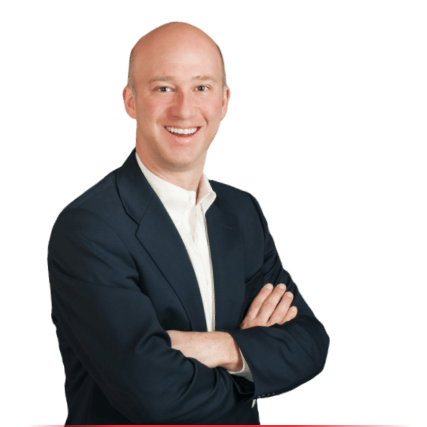 Smiling bald man in a navy blue suit jacket and white dress shirt with arms crossed, isolated on a white background.