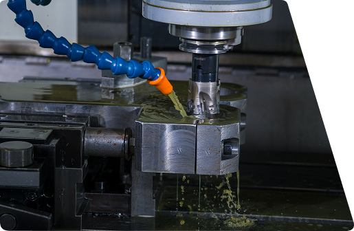 CNC milling machine cutting a metal workpiece with coolant being applied from a blue nozzle.