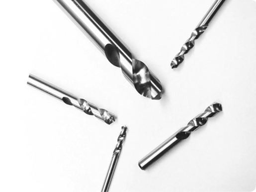 Five metallic twist drill bits of varying sizes arranged on a plain white background.