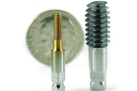 Small and large metal threading taps standing vertically in front of a US dime.