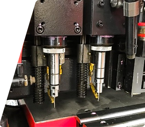 Close-up of industrial machinery featuring two vertical drilling spindles with metal components and mechanical connections.